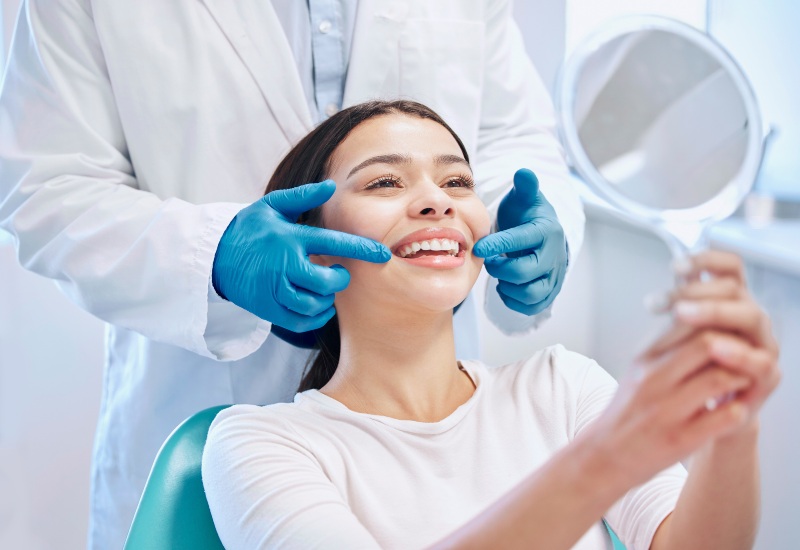 A happy patient checks teeth after a dental cleaning, promoting the importance of regular oral care