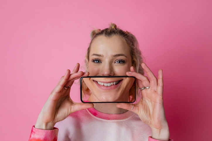 Person framing bright smile on phone for teeth whitening trends in South Bend, IN